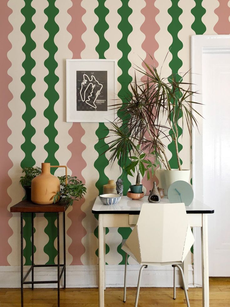 a room with a table, chair and potted plant on the wall next to it