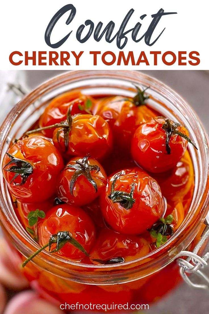 a glass jar filled with cherry tomatoes on top of a wooden table next to a hand holding