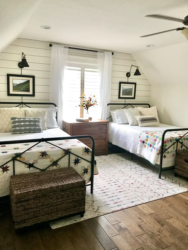 two beds in a bedroom with white walls and wood floors