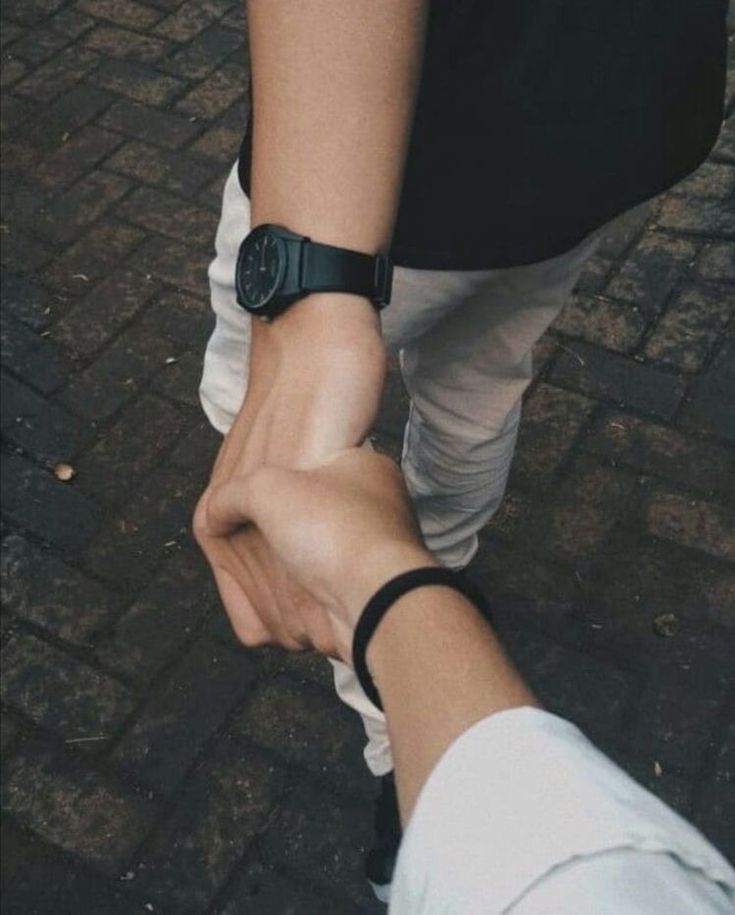 two people holding hands while walking down the street