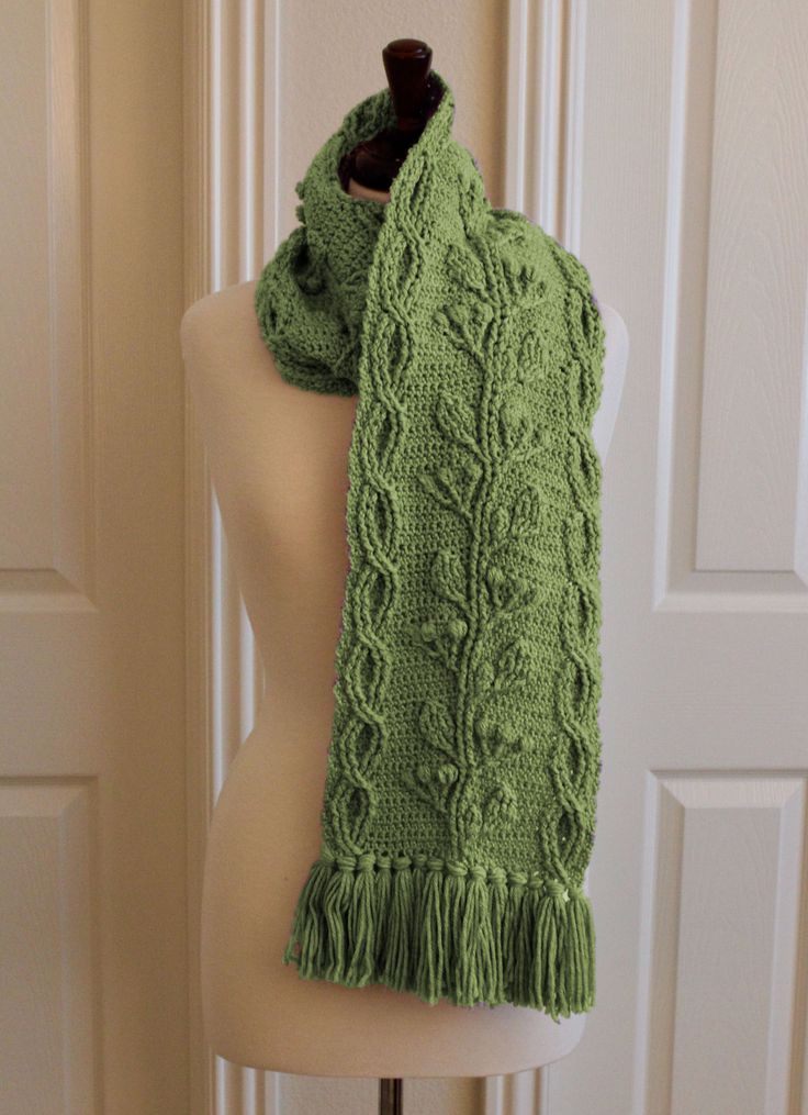 a green knitted scarf sitting on top of a mannequin