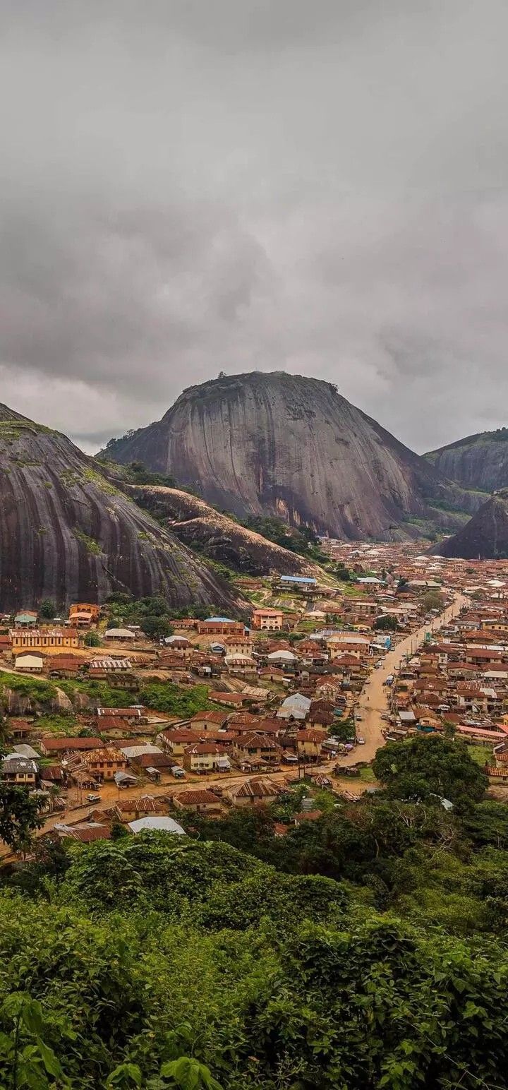 an aerial view of a small town in the middle of a mountain range with trees and bushes