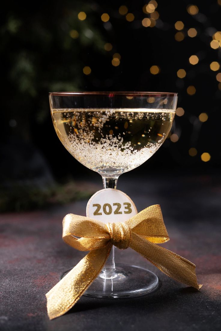 a wine glass filled with white wine and topped with a gold bow on the side