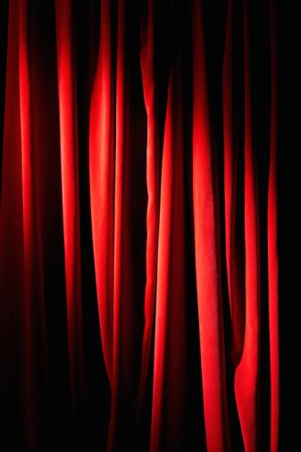 the curtains are red and black in this dark room with only one light on them