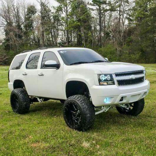 a white truck parked on top of a lush green field