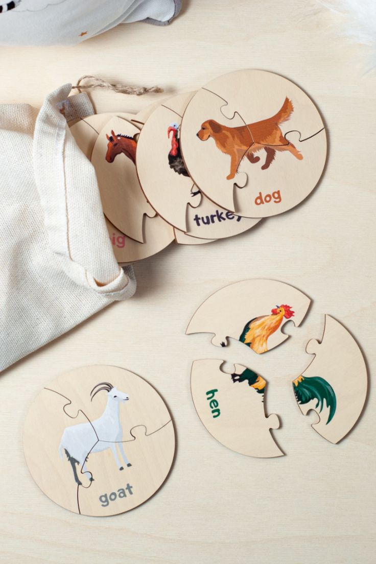 four wooden puzzles with different animals on them and a drawstring bag in the background