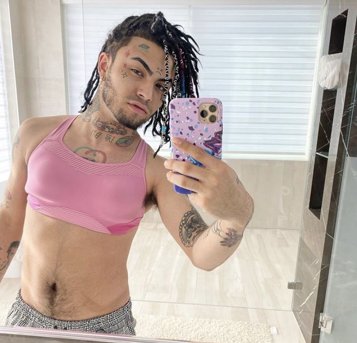 a man with dreadlocks taking a selfie in front of a bathroom mirror