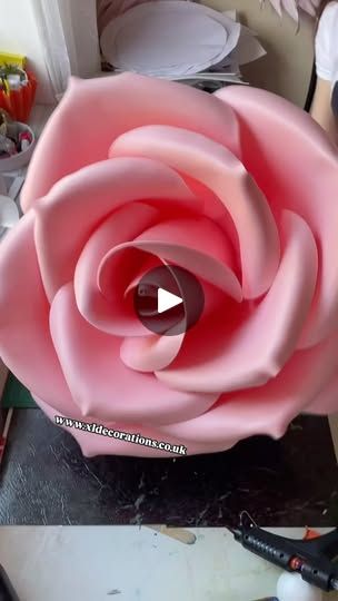 a large pink rose being made out of paper