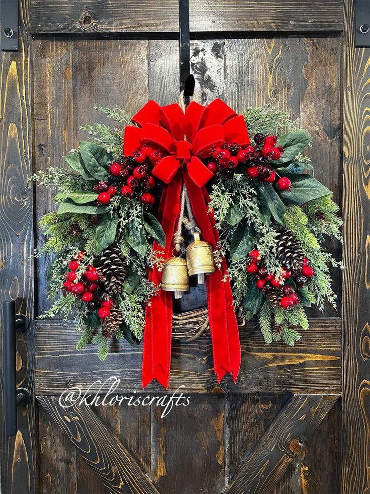 a christmas wreath hanging on the side of a wooden door with bells and evergreens