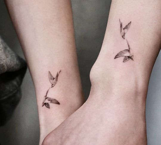 two people holding hands with small tattoos on their wrist and one has a bird flying above them