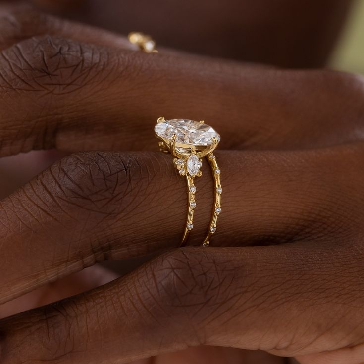 a close up of a person's hand with a ring on their finger and the other hand holding an engagement ring