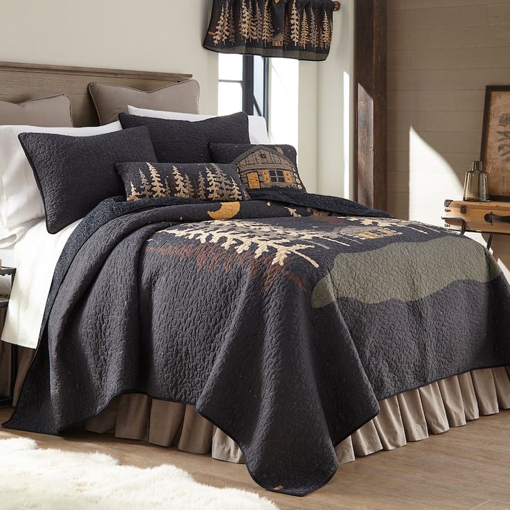 a bed with a black comforter and pillows on top of it in a room