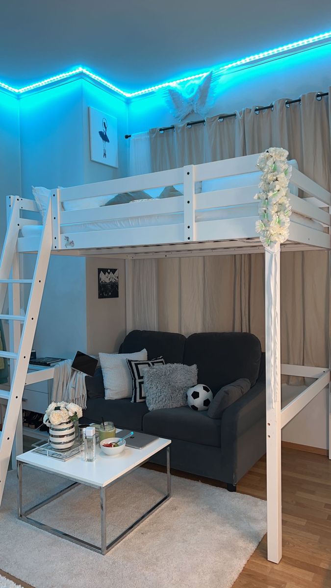 a white loft bed sitting next to a couch in a living room under a blue light