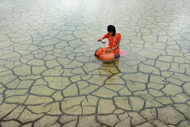 a woman sitting on the ground in shallow water