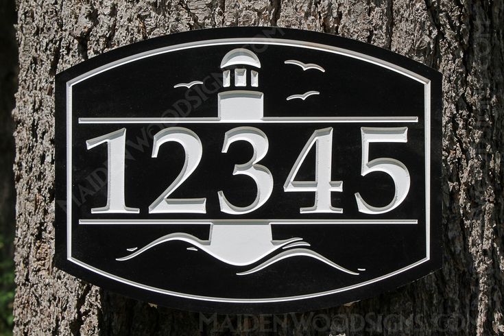 a black and white house number sign on a tree