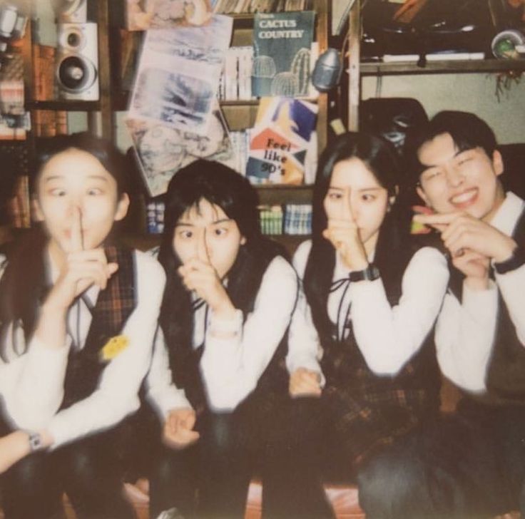 four young people posing for a photo in front of a bookshelf