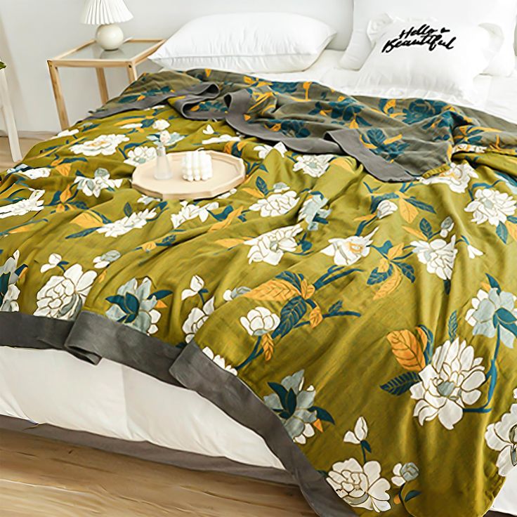 a bed with a green floral comforter on top of it next to a night stand