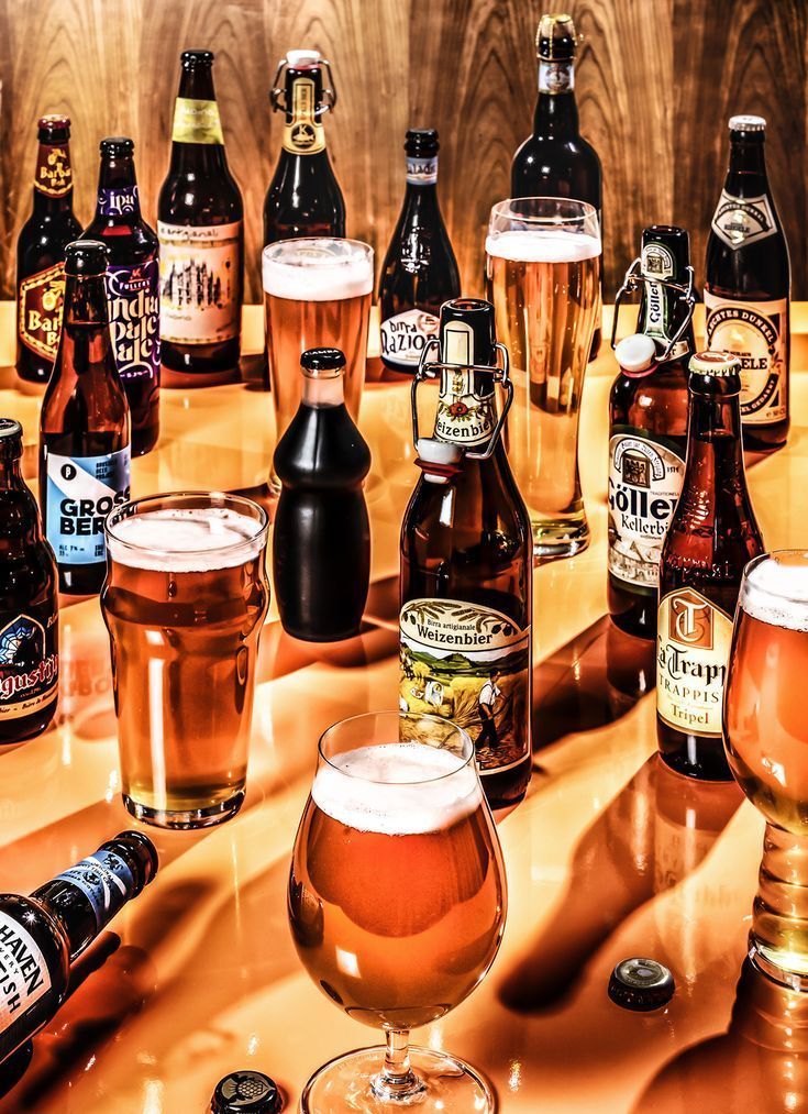 a table topped with lots of different types of beer bottles and glasses next to each other