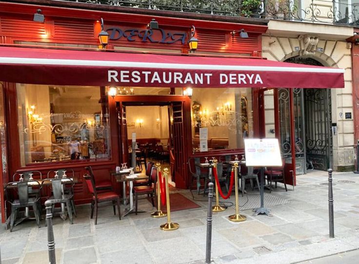 a restaurant with red awnings and tables outside