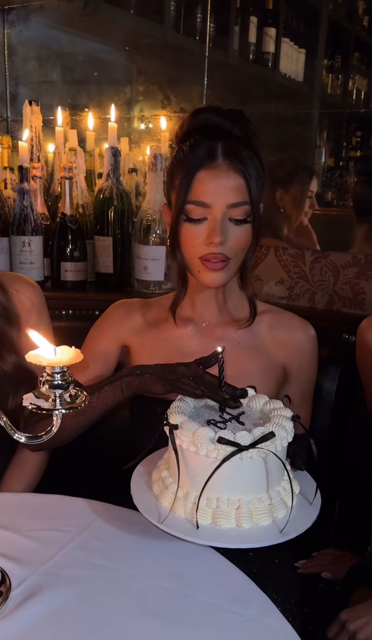 a woman sitting at a table in front of a cake with a candle on it