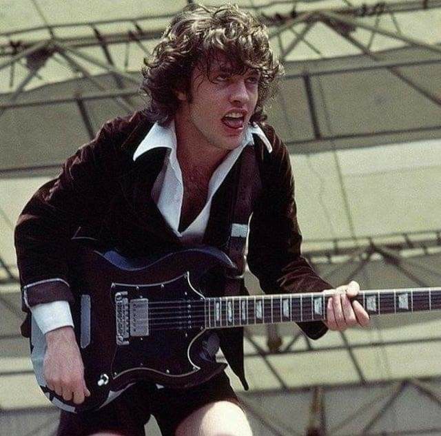 a young man playing an electric guitar on stage