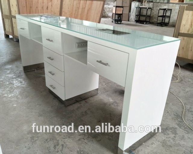 an office desk with glass top and drawers in the middle of a warehouse flooring area