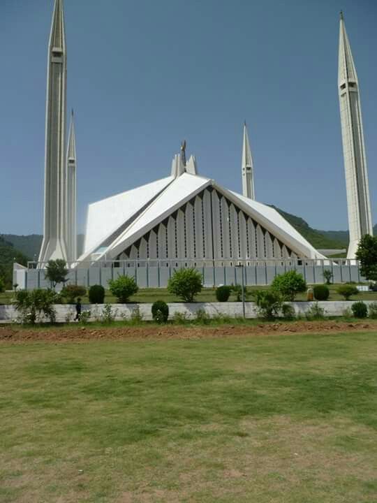 a large white building with three spires on it's side and grass in front