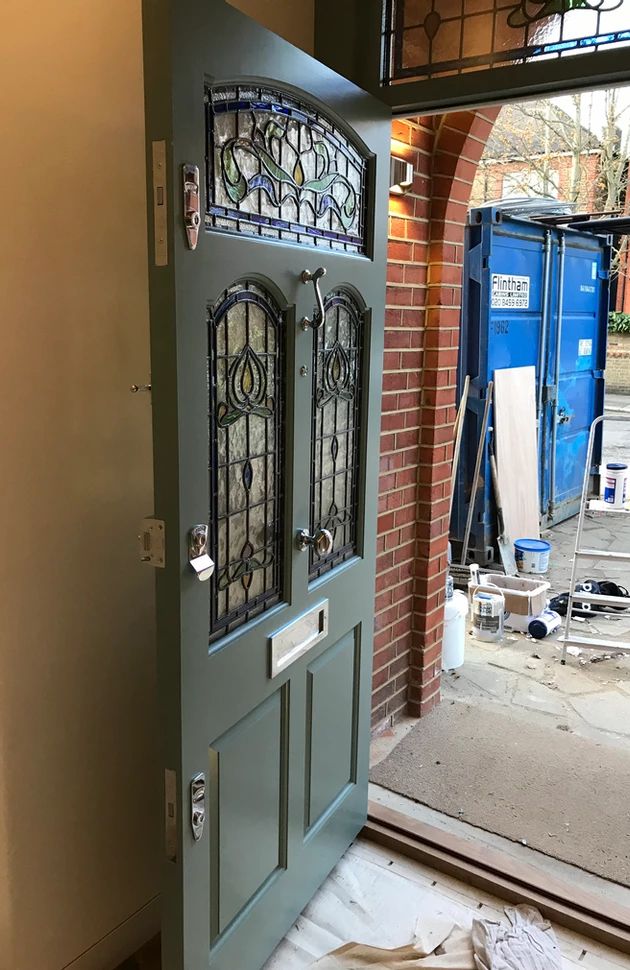 the front door is being painted green and has stained glass panels on it's sides