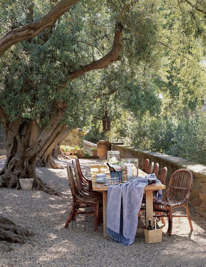 an outdoor table with chairs and a blue blanket on it in front of some trees