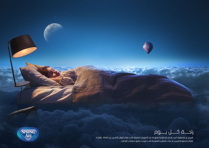 a man laying in bed under a night sky with hot air balloons floating above him