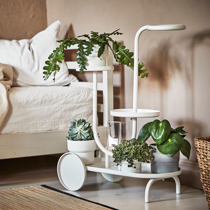 there is a white plant stand on the floor next to a bed with plants in it