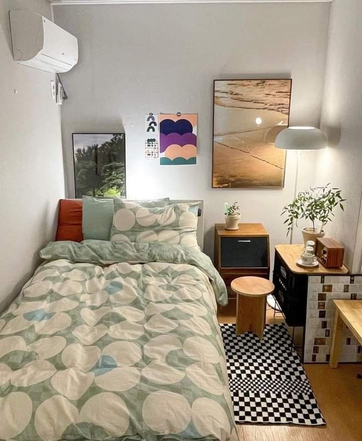 a bed sitting in a bedroom next to a wooden table and two pictures on the wall