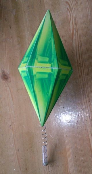 a green origami kite sitting on top of a wooden table next to a screwdriver