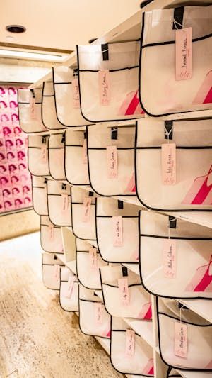 several rows of white baskets with pink tags on them in a room filled with shelves