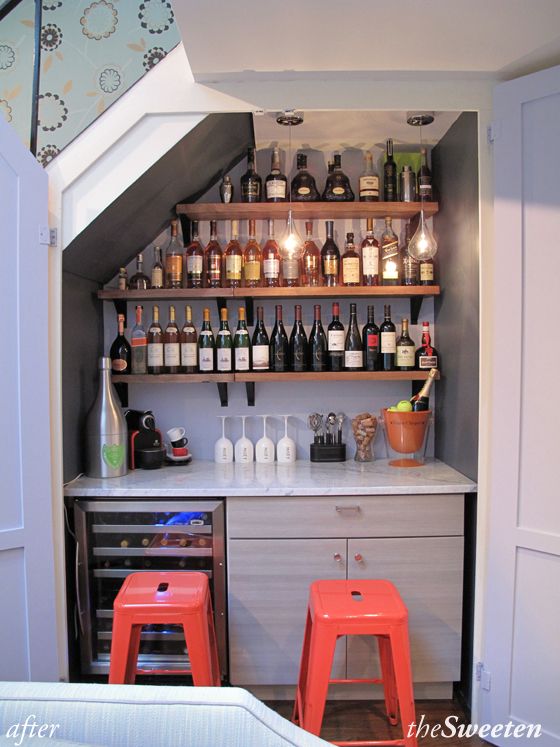 a small bar with stools and bottles on the shelves