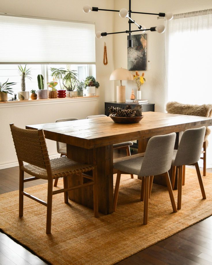 a dining room table with four chairs and a rug on the floor in front of it