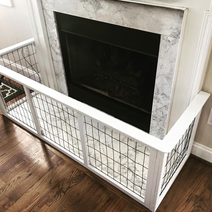 a fireplace with a white marble surround and black iron grills on the top shelf