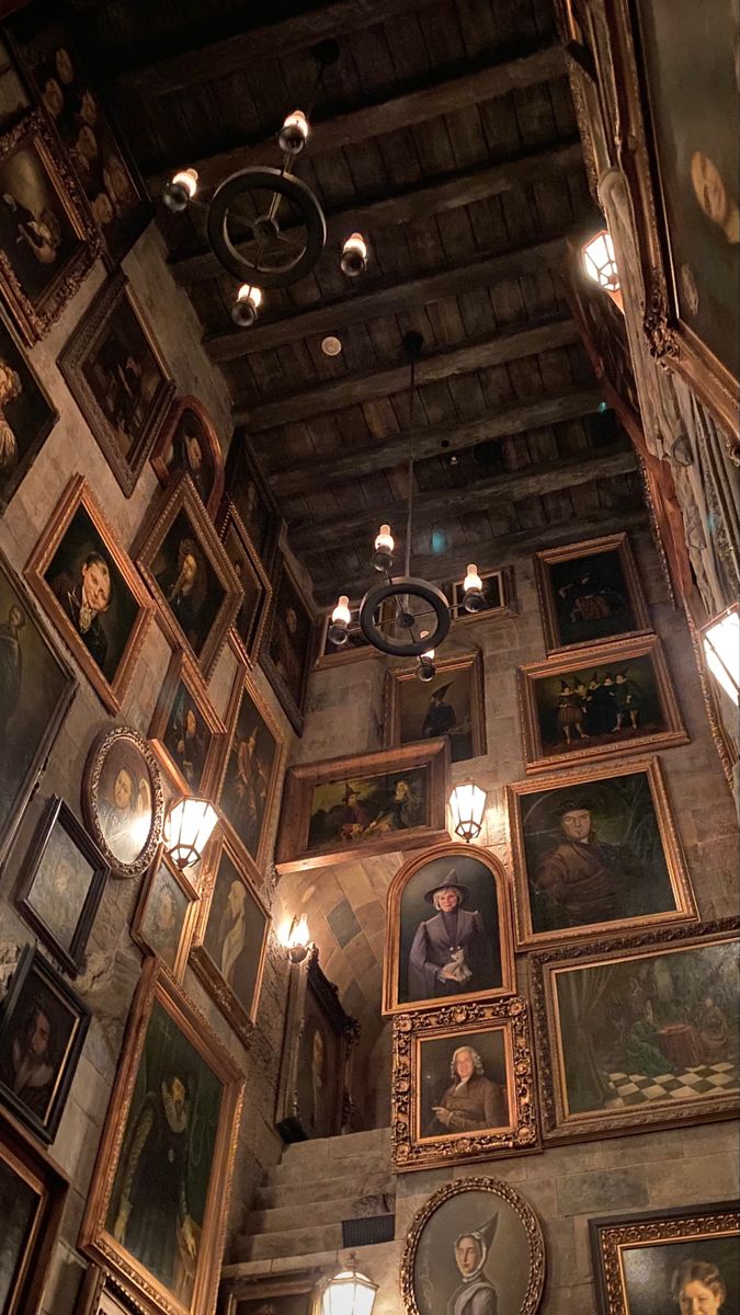 a room filled with lots of paintings and lights hanging from the ceiling next to a chandelier