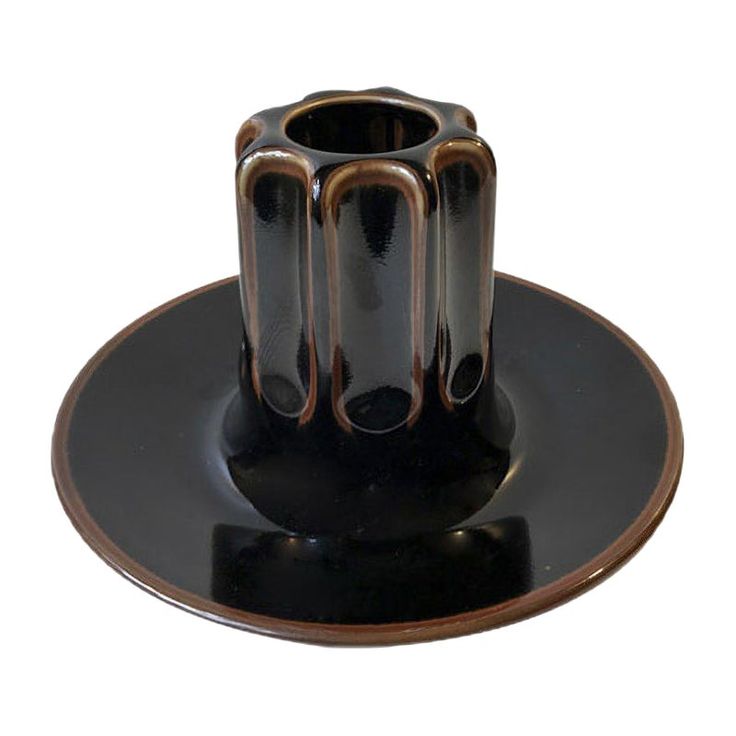 a black and brown vase sitting on top of a plate with saucer underneath it