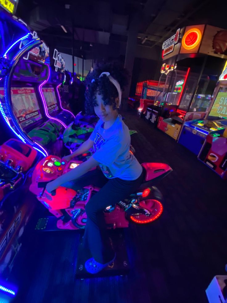 a young person on a motor bike in a room with neon lights and arcade machines