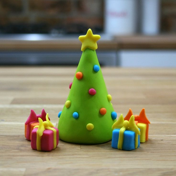 a green christmas tree surrounded by presents on a wooden table with a blurry background