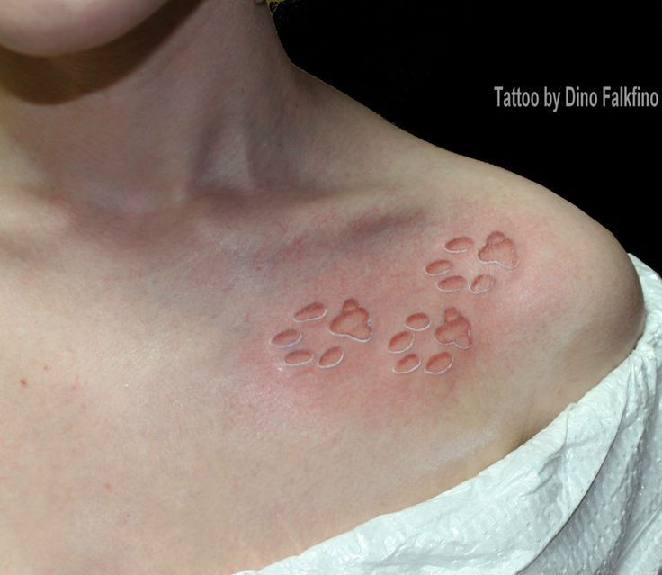 a woman's chest with red spots on her left side and paw prints across the chest