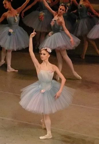 a group of ballerinas in blue tutus and ballet shoes with their arms raised