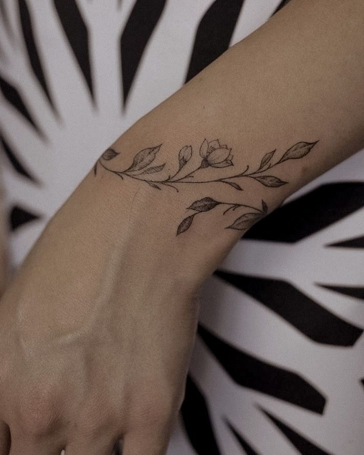 a woman's hand with a small flower tattoo on her left arm and wrist