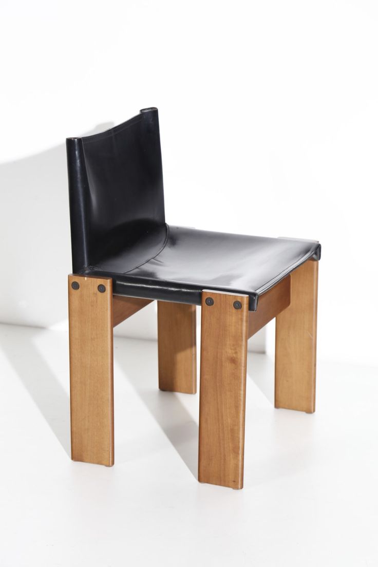 a black leather chair sitting on top of a wooden table next to a white wall