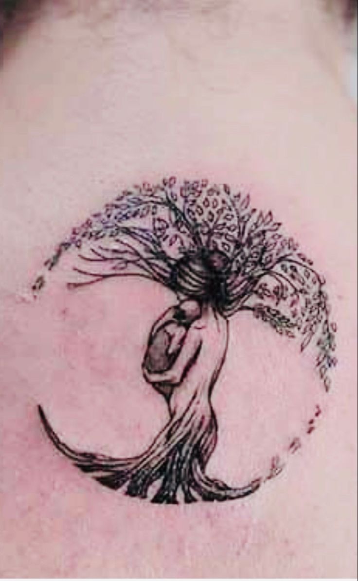 a woman's back with a tree tattoo on it