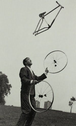 a man holding two large metal objects in his hands while standing on top of a grass covered field