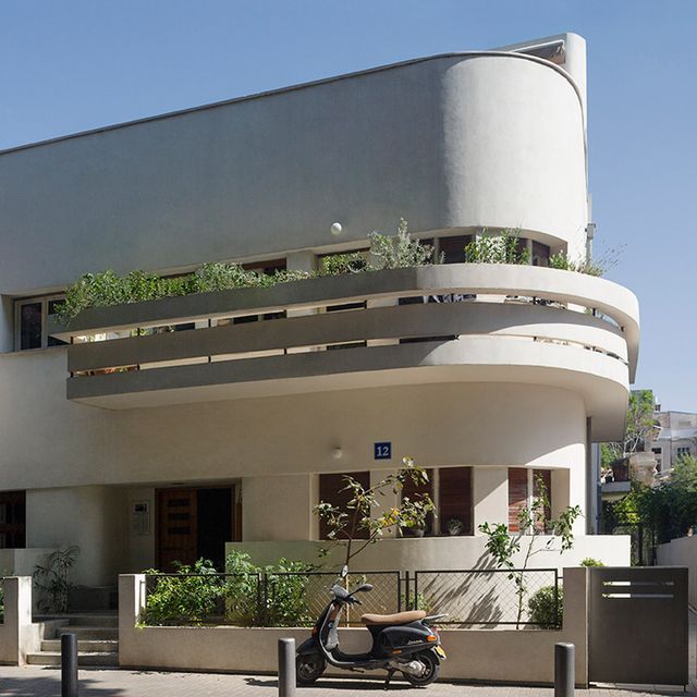 a scooter parked in front of a building with plants growing on the balconies