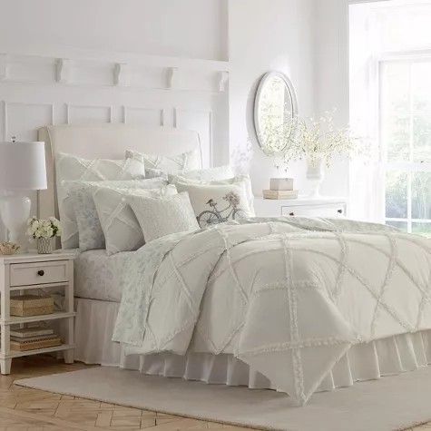 a white bed in a bedroom next to a window