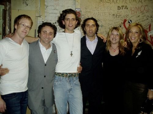 a group of people standing next to each other in front of a wall with graffiti on it